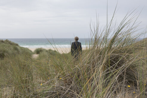 UK, Cornwall, Hayle, Geschäftsmann steht in den Stranddünen und betrachtet die Aussicht - PSTF00080
