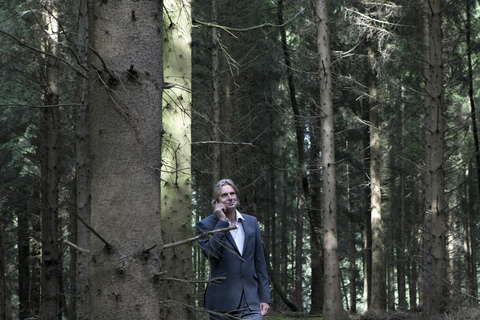 Geschäftsmann mit Mobiltelefon im Wald, lizenzfreies Stockfoto