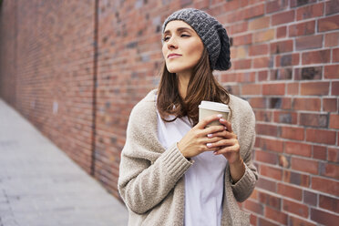 Portrait of daydreaming young woman with coffee to go - BSZF00215