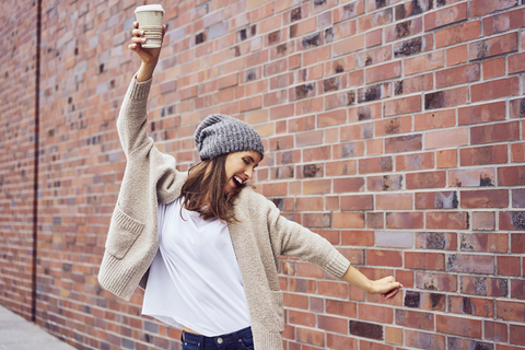 Happy woman with coffee to go singing and dancing on the street stock photo