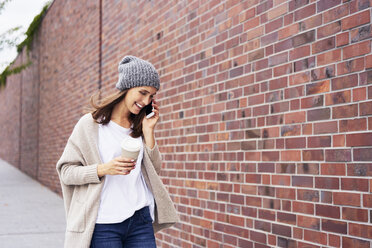 Happy woman with coffee to go on the phone - BSZF00221