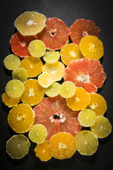 Sliced citrus fruits on black ground - MAEF12515