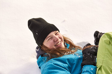 Lachende junge Frau im Schnee liegend - JEDF00299