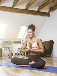 Porträt einer lächelnden jungen Frau, die Yoga praktiziert - MADF01374