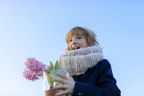 Porträt eines glücklichen Jungen mit getopften Hyazinthen vor blauem Himmel - KMKF00154