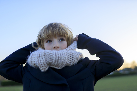 Boy with knitted round scarf at sunset stock photo