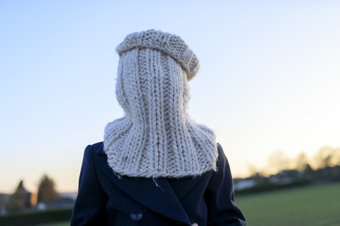 Boy covering his face with knitted round scarf stock photo