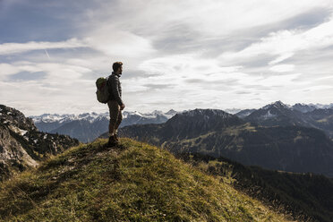 Österreich, Tirol, junger Mann steht in einer Berglandschaft und betrachtet die Aussicht - UUF12555