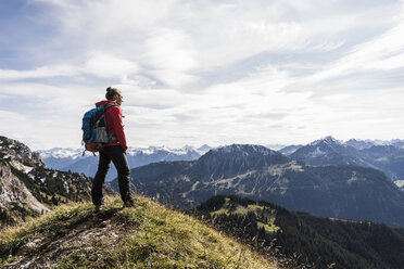 Österreich, Tirol, junge Frau steht in einer Berglandschaft und betrachtet die Aussicht - UUF12561
