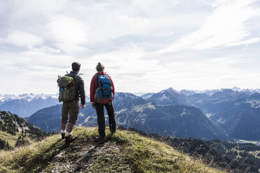 Österreich, Tirol, junges Paar steht in einer Berglandschaft und betrachtet die Aussicht - UUF12562