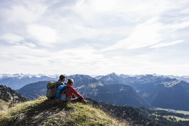 Österreich, Tirol, junges Paar sitzt in einer Berglandschaft und betrachtet die Aussicht - UUF12564