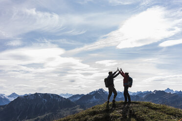Austria, Tyrol, young couple standing in mountainscape cheering - UUF12565