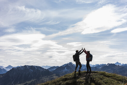 Österreich, Tirol, junges Paar steht in Berglandschaft und jubelt - UUF12565