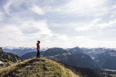 Österreich, Tirol, junge Frau steht in einer Berglandschaft und betrachtet die Aussicht - UUF12569
