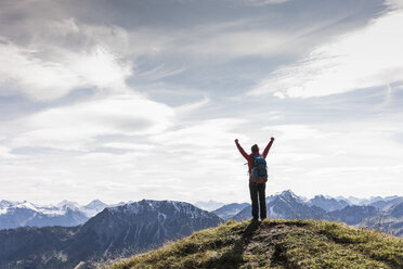 Austria, Tyrol, young woman standing in mountainscape cheering - UUF12570