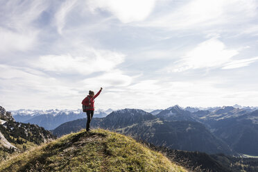 Austria, Tyrol, young woman standing in mountainscape cheering - UUF12572