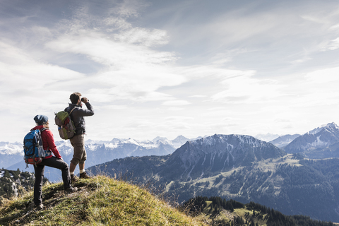 Österreich, Tirol, junges Paar steht in einer Berglandschaft und betrachtet die Aussicht, lizenzfreies Stockfoto