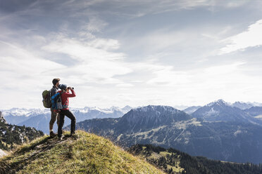 Österreich, Tirol, junges Paar steht in einer Berglandschaft und betrachtet die Aussicht - UUF12576