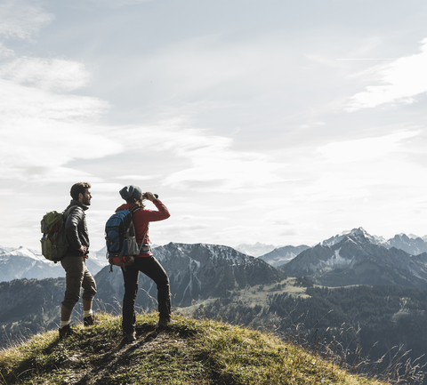 Österreich, Tirol, junges Paar steht in einer Berglandschaft und betrachtet die Aussicht, lizenzfreies Stockfoto