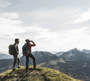Österreich, Tirol, junges Paar steht in einer Berglandschaft und betrachtet die Aussicht - UUF12577