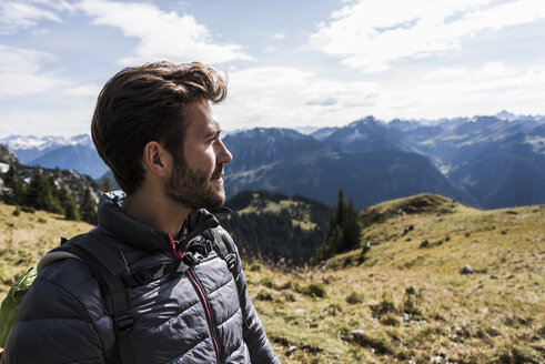 Österreich, Tirol, Porträt eines jungen Mannes in einer Berglandschaft mit Blick auf die Aussicht - UUF12580