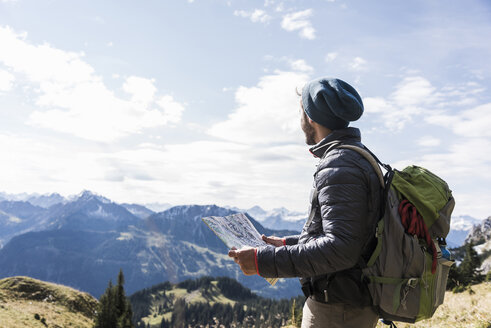 Österreich, Tirol, junger Mann mit Landkarte in Berglandschaft - UUF12583