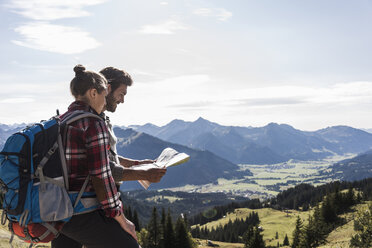 Österreich, Tirol, junges Paar mit Blick auf Karte in Berglandschaft - UUF12591