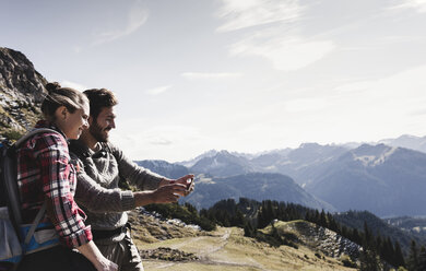 Austria, Tyrol, smiling young couple taking a selfie in mountainscape - UUF12595