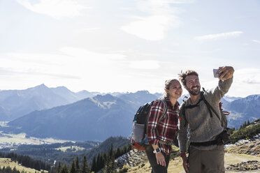 Österreich, Tirol, lächelndes junges Paar macht ein Selfie in einer Berglandschaft - UUF12596