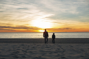 Vater und Sohn gehen bei Sonnenuntergang am Strand spazieren - EBSF02016