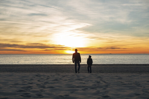 Vater und Sohn gehen bei Sonnenuntergang am Strand spazieren - EBSF02016