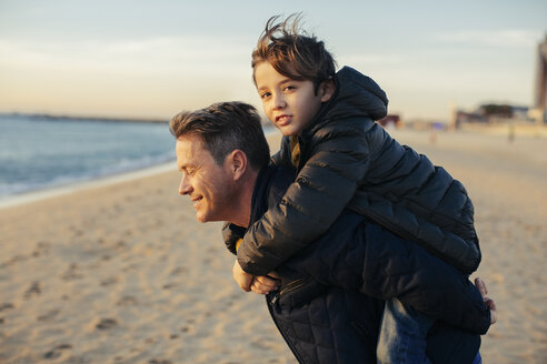 Porträt eines Vaters, der seinen Sohn am Strand huckepack trägt - EBSF02021