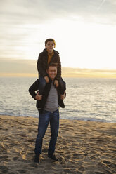 Porträt eines Vaters, der seinen Sohn am Strand huckepack trägt - EBSF02031