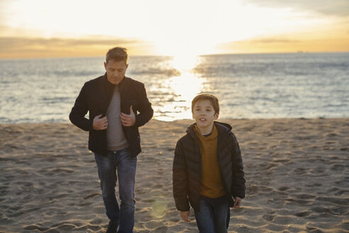 Vater und Sohn gehen bei Sonnenuntergang am Strand spazieren - EBSF02034