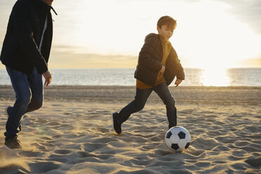 Vater und Sohn spielen Fußball am Strand bei Sonnenuntergang - EBSF02043