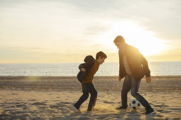 Vater und Sohn spielen Fußball am Strand bei Sonnenuntergang - EBSF02044