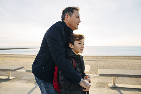 Vater und Sohn mit Motorroller auf der Strandpromenade bei Sonnenuntergang - EBSF02049