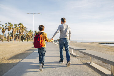 Father and son walking on beach promenade - EBSF02060