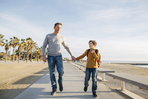Vater und Sohn gehen auf der Strandpromenade spazieren, lizenzfreies Stockfoto