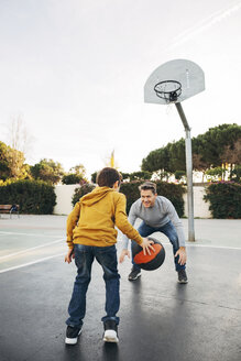 Vater und Sohn spielen Basketball auf einem Platz im Freien - EBSF02062