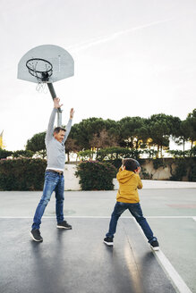 Vater und Sohn spielen Basketball auf einem Platz im Freien - EBSF02063