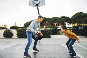 Vater und Sohn spielen Basketball auf einem Platz im Freien - EBSF02064