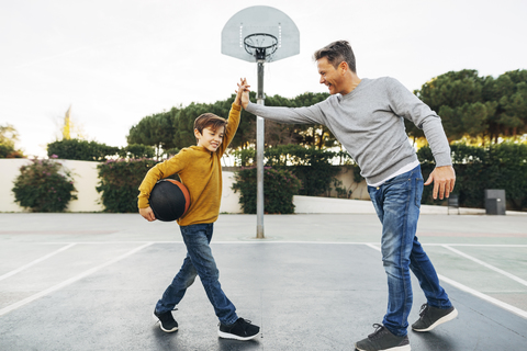 Vater und Sohn geben sich auf dem Basketballplatz im Freien die Hand, lizenzfreies Stockfoto