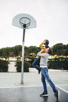 Vater hebt Sohn auf Basketballplatz im Freien hoch - EBSF02071