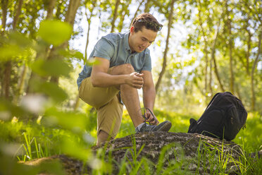 Man tying his shoes in the forest - ZEF14945