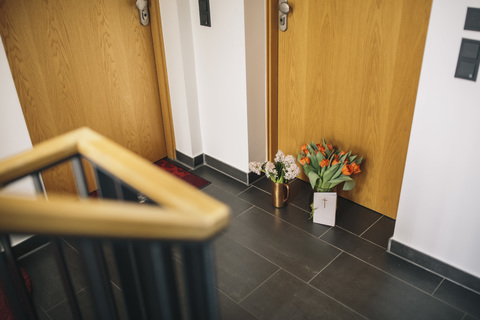 Abschiedsblumen, Kerze und Beileidskarte an der Wohnungstür eines verstorbenen Nachbarn, lizenzfreies Stockfoto