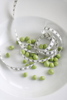 Green peas with measuring tape on a plate - HSTF00053