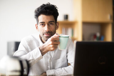 Porträt eines entspannten Geschäftsmannes mit Tasse am Schreibtisch im Büro - SGF02155