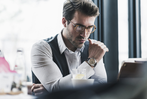 Seriöser junger Mann mit Tablet in einem Café, lizenzfreies Stockfoto