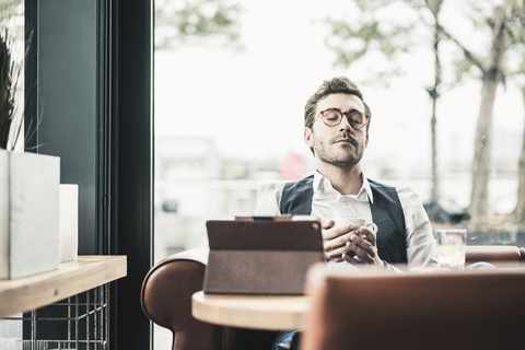 Young man in a cafe with tablet cup of coffee relaxing stock photo